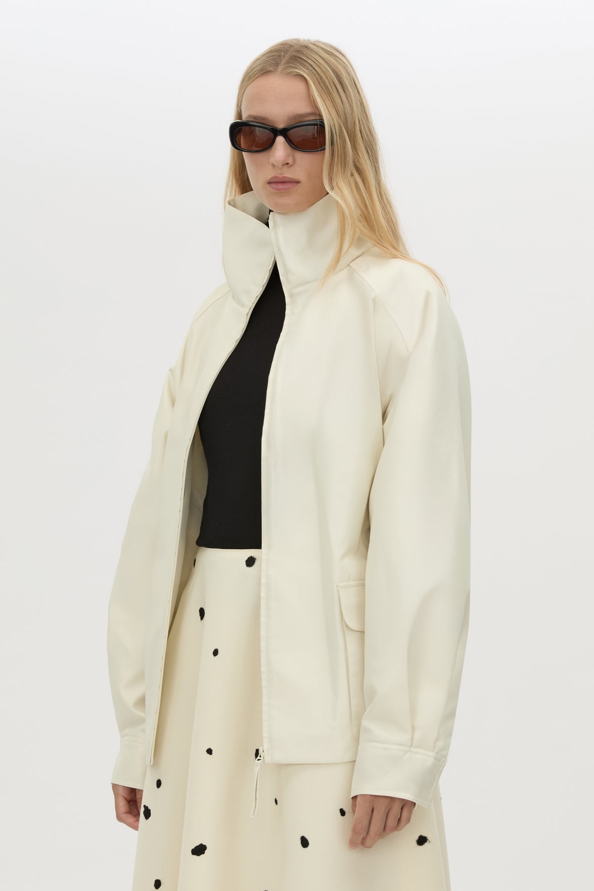 Front styled view CAMILLA AND MARC Drea funnel neck puffer jacket in cream with utility waistbelt and detachable throat latch.