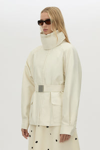 3/4 view CAMILLA AND MARC Drea funnel neck puffer jacket in cream with utility waistbelt and detachable throat latch.