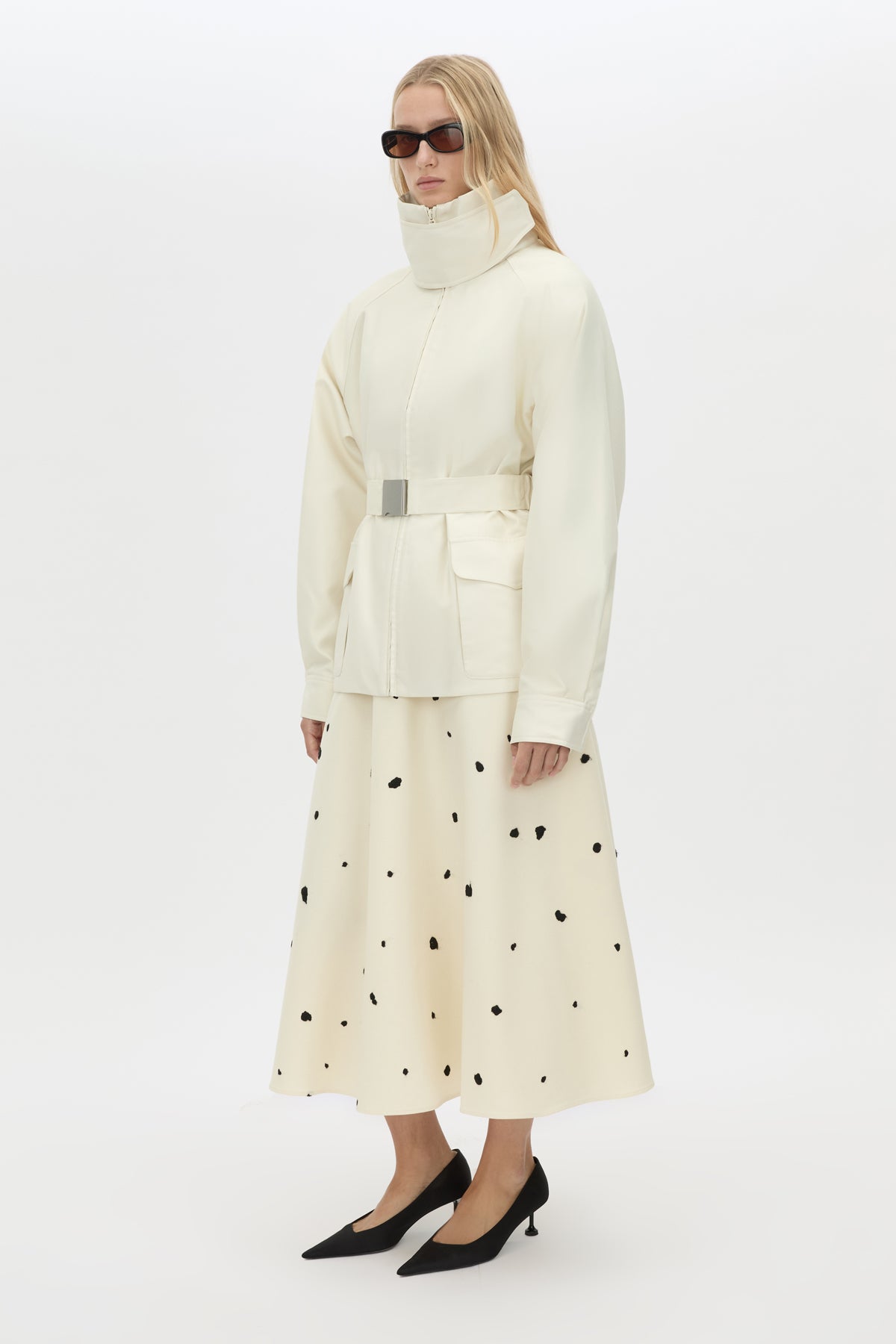 Side styled view CAMILLA AND MARC Drea funnel neck puffer jacket in cream with utility waistbelt and detachable throat latch.