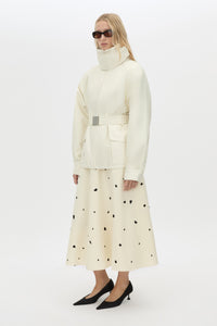 Side styled view CAMILLA AND MARC Drea funnel neck puffer jacket in cream with utility waistbelt and detachable throat latch.