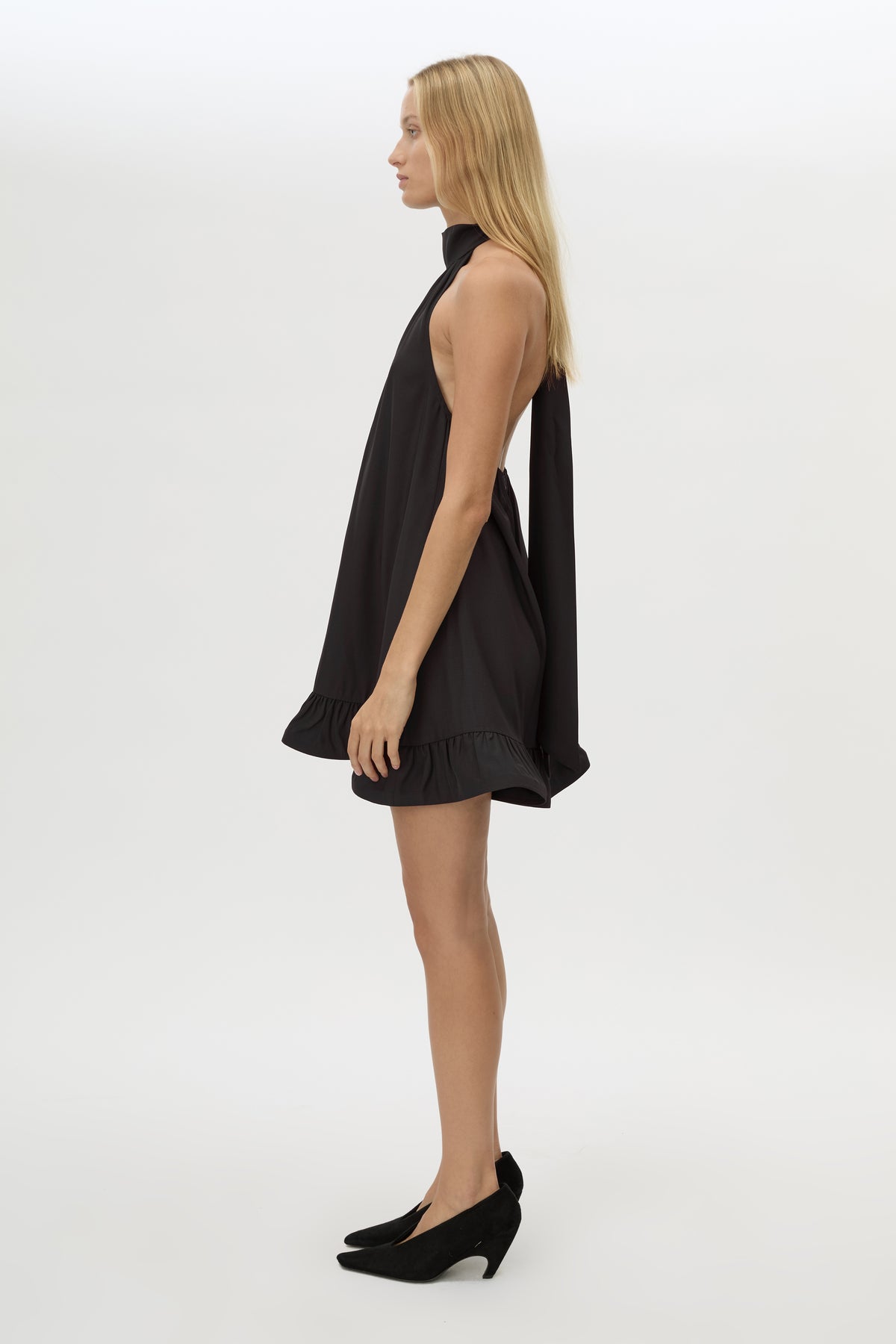 Side view CAMILLA AND MARC Elsen Halter Mini Dress in Black with open back, tie‑up neck and fluted crinoline hem.
