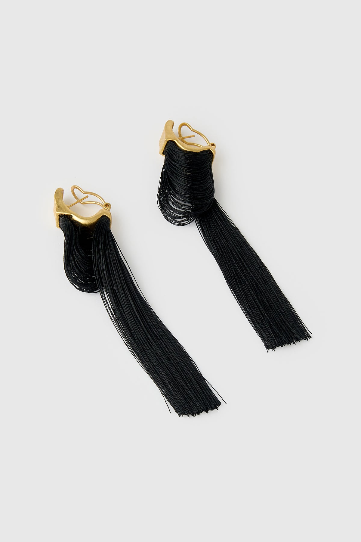 Three-quarter view CAMILLA AND MARC Friesian Drop Earrings with 18k gold plating, featuring draped black tassel drop fringing.