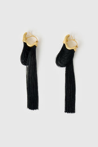 Side view CAMILLA AND MARC Friesian Drop Earrings with 18k gold plating, featuring draped black tassel drop fringing.