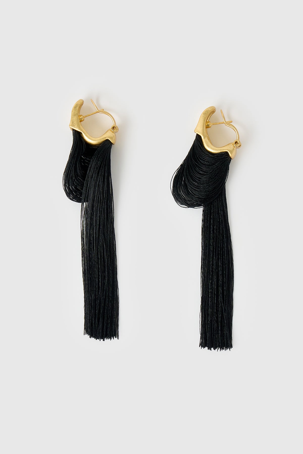 Side ghost view CAMILLA AND MARC Friesian Drop Earrings with 18k gold plating, featuring draped black tassel drop fringing.