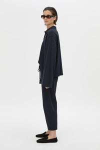 Side view CAMILLA AND MARC Moreno Pique Track Pant in navy with elastic‑encased waistband and embroidered eyelets and drawcord.