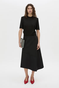 Styled view CAMILLA AND MARC high-waisted Namira Midi Skirt in black with asymmetric hemline.