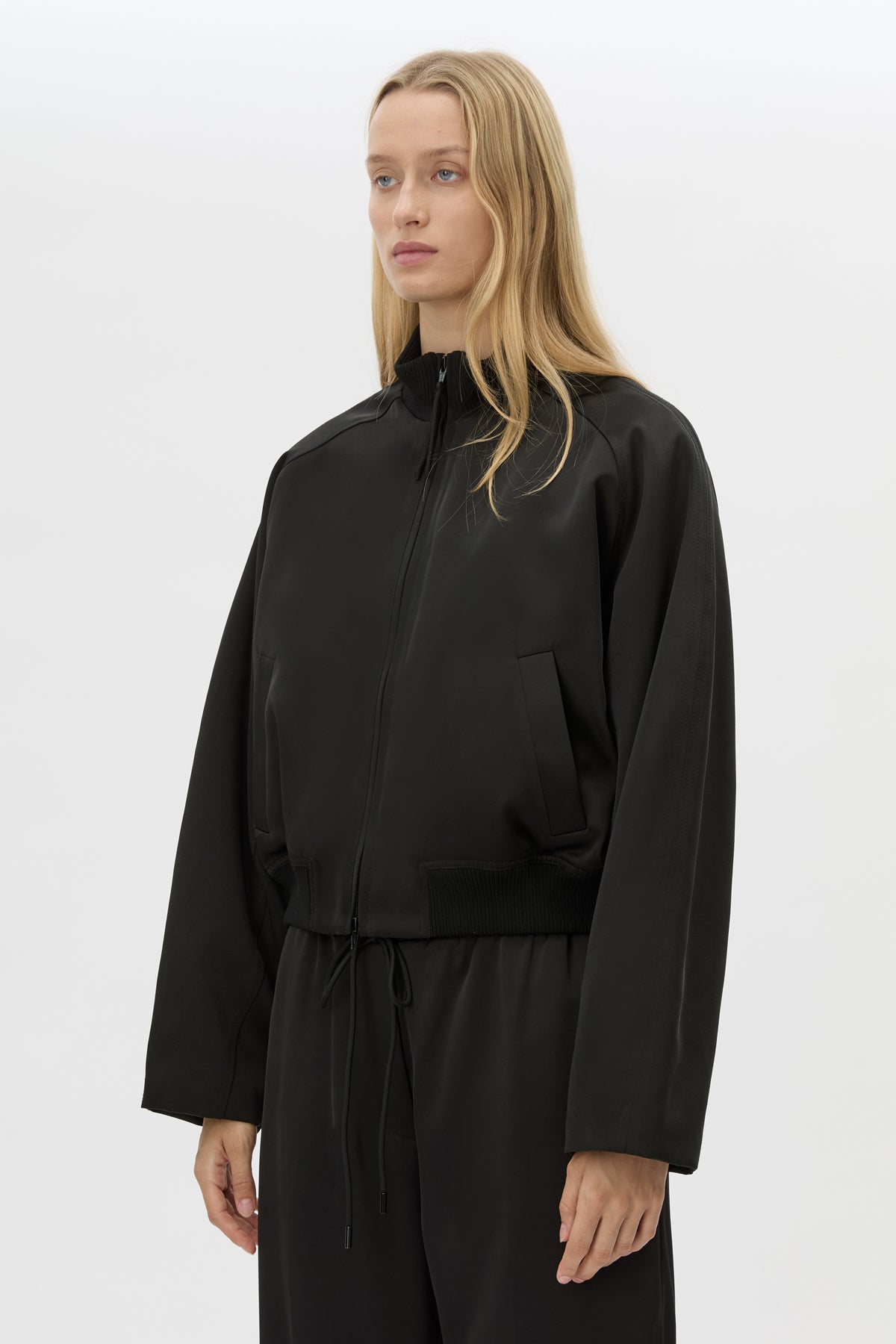Cropped view CAMILLA AND MARC Tamar Satin Bomber Jacket in black with front zipper.