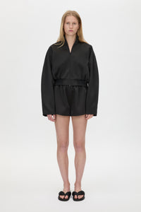 Front styled view CAMILLA AND MARC Tamar Satin Bomber Jacket in Black with front zipper.
