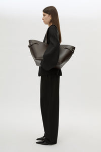 Styled view CAMILLA AND MARC Willa Tote in Chocolate Brown with side strap and buckle detailing and magnetic button closure.
