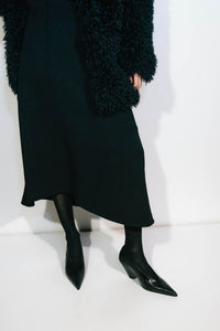 Campaign styled view CAMILLA AND MARC high-waisted Namira Midi Skirt in black with asymmetric hemline.